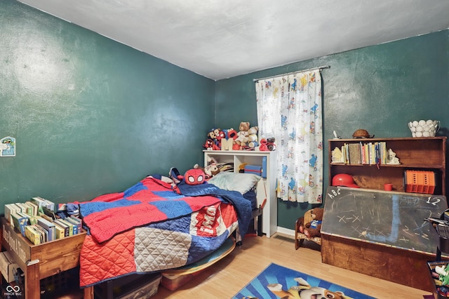 bedroom with a textured wall and wood finished floors