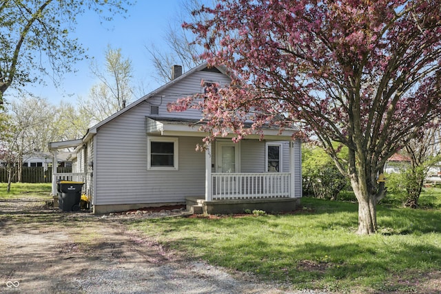 bungalow-style house featuring a chimney, covered porch, and a front yard