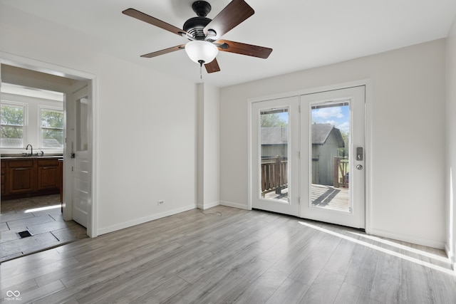 911 W Washington Ave, Shelbyville, IN 46176 - spare room featuring light wood-type flooring, a sink, ceiling fan, and plenty of natural light