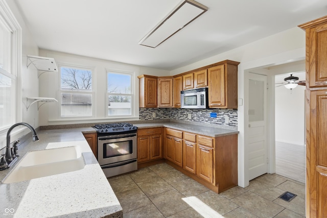 911 W Washington Ave, Shelbyville, IN 46176 - kitchen featuring tasteful backsplash, appliances with stainless steel finishes, brown cabinets, a sink, and visible vents
