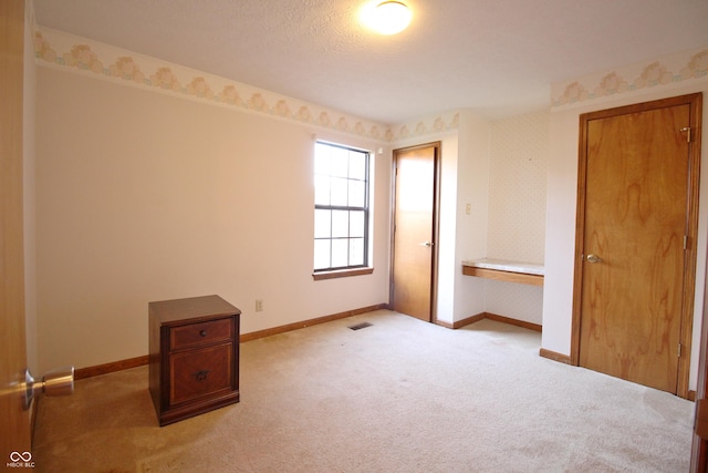 unfurnished bedroom with wallpapered walls, visible vents, carpet flooring, and baseboards