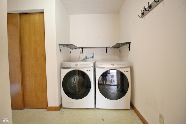 washroom with light floors, baseboards, washer and clothes dryer, and laundry area