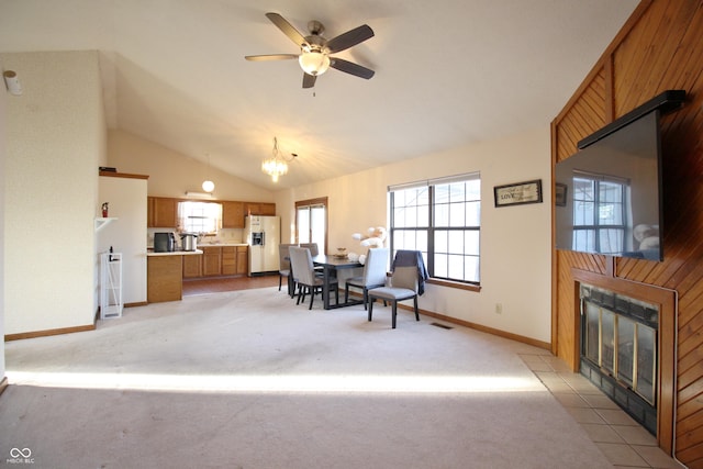 dining space featuring a fireplace with flush hearth, light carpet, baseboards, visible vents, and ceiling fan with notable chandelier