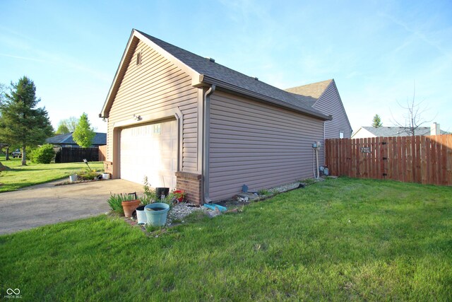 view of home's exterior with a yard, a detached garage, concrete driveway, and fence