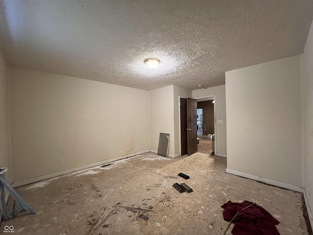 spare room featuring a textured ceiling and baseboards