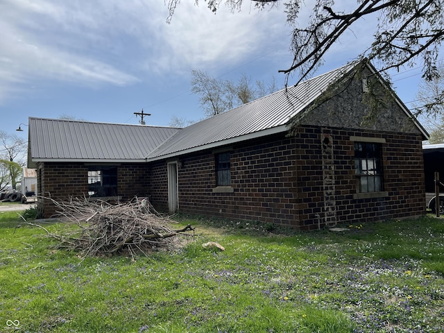 view of side of home with a lawn, metal roof, and brick siding