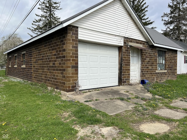 view of property exterior with a yard, brick siding, and a garage