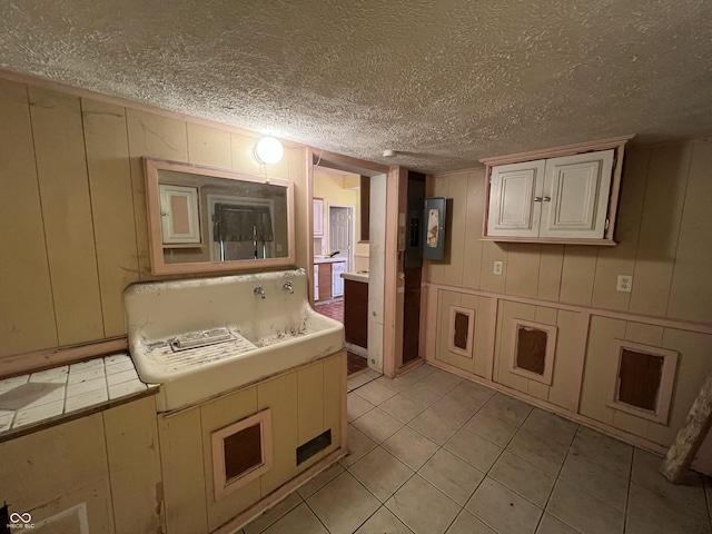 bathroom with tile patterned floors, a textured ceiling, and a decorative wall