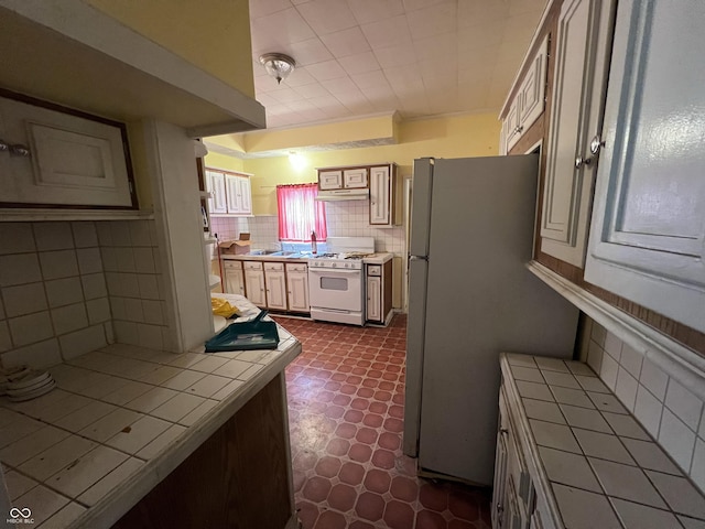 kitchen featuring dark floors, white appliances, decorative backsplash, and tile countertops