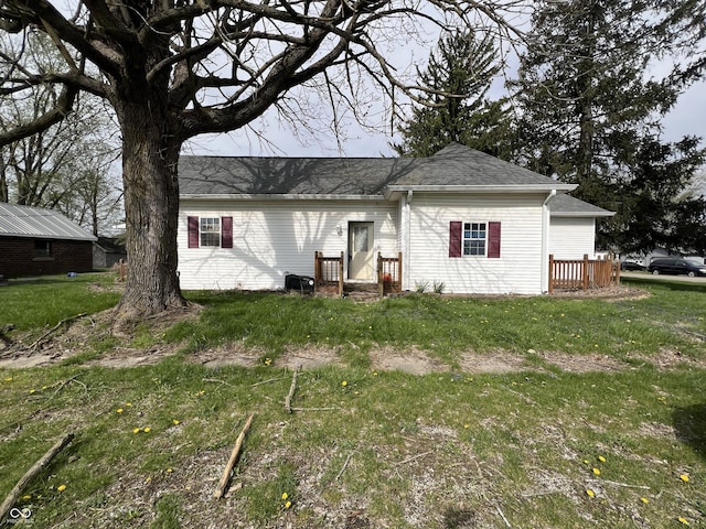 rear view of house with a yard and roof with shingles