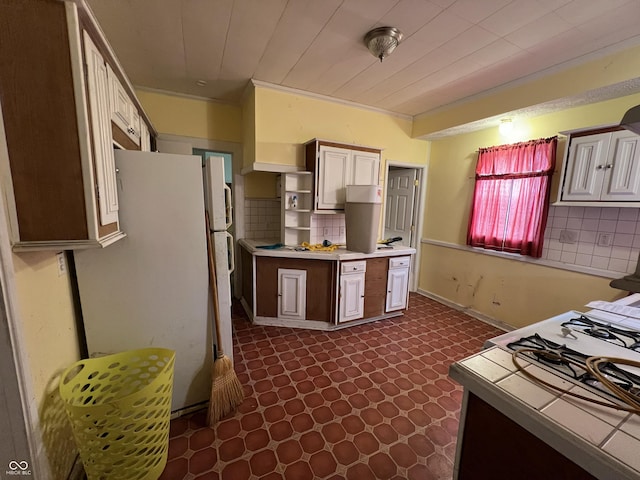 kitchen featuring open shelves, light countertops, freestanding refrigerator, and backsplash
