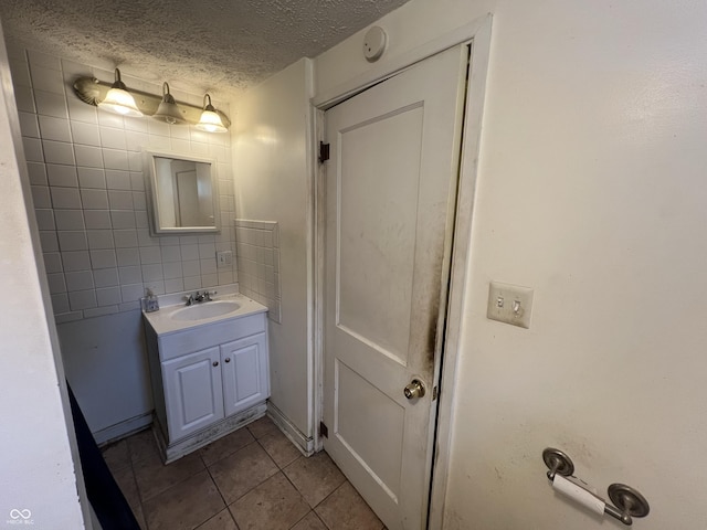 bathroom with tile patterned floors, a textured ceiling, and vanity