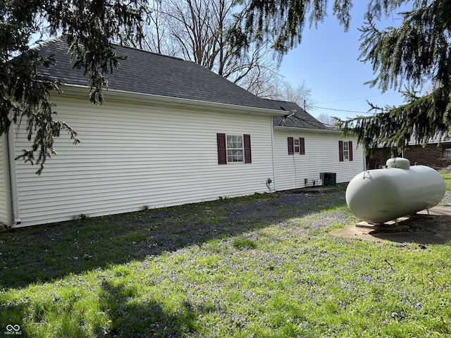 view of property exterior featuring a lawn, central air condition unit, and a shingled roof