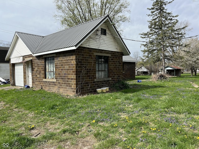 view of side of property featuring a garage, a yard, and metal roof