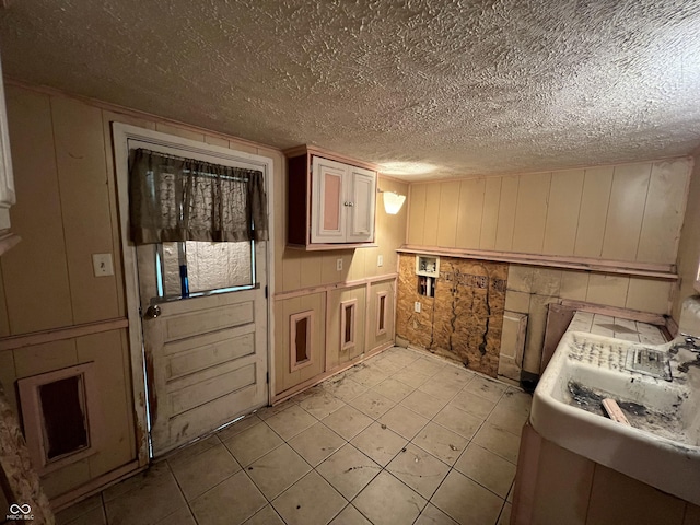 kitchen featuring light tile patterned floors, a textured ceiling, a decorative wall, and light countertops