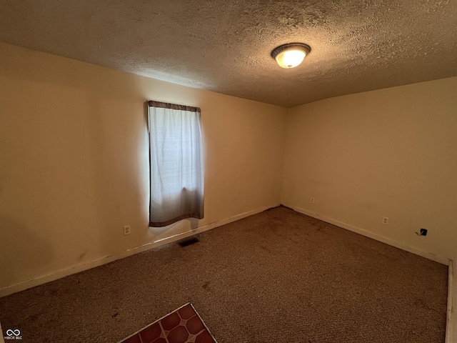 spare room with a textured ceiling, visible vents, carpet flooring, and baseboards