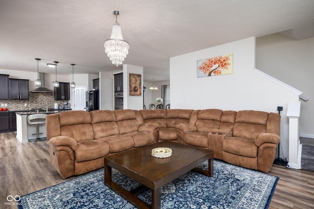 living area featuring an inviting chandelier, light wood-style floors, and baseboards