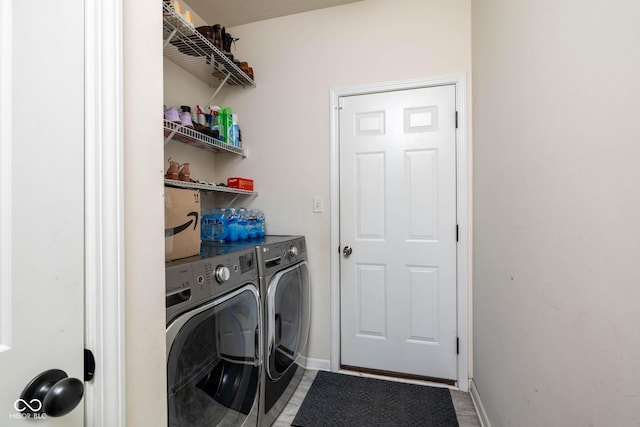 washroom with washing machine and clothes dryer, laundry area, and baseboards