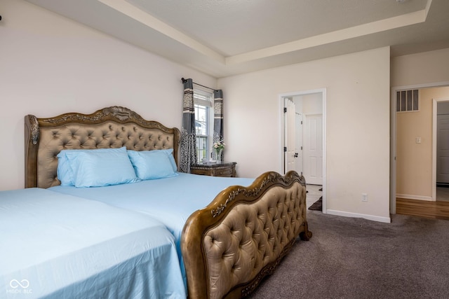 bedroom with a tray ceiling, carpet, visible vents, and baseboards