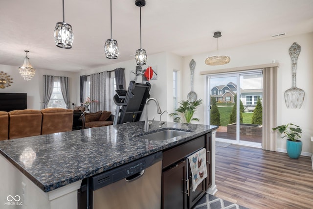 kitchen with stainless steel dishwasher, a sink, open floor plan, visible vents, and wood finished floors