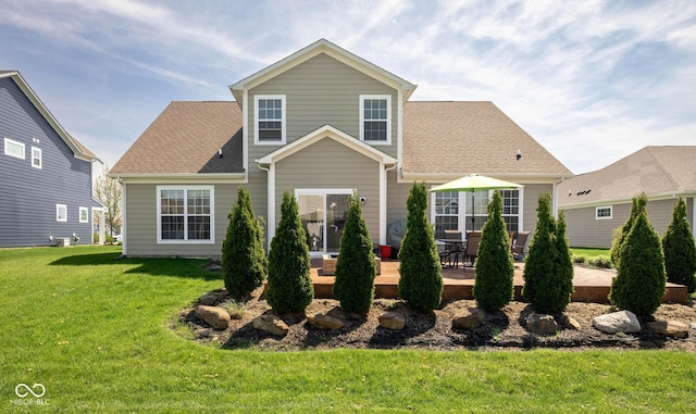 view of front facade with a patio area, roof with shingles, and a front yard