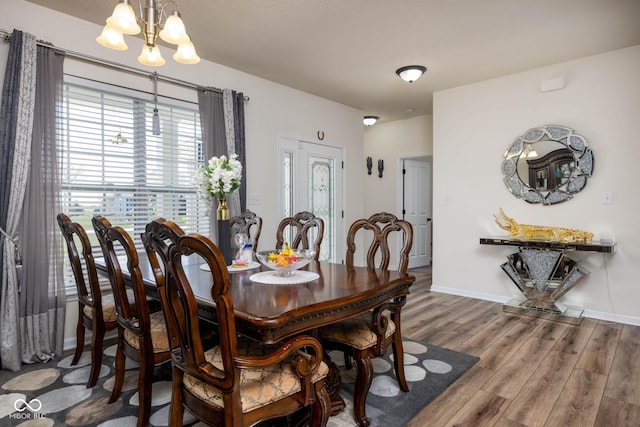 dining area with baseboards, wood finished floors, and a chandelier