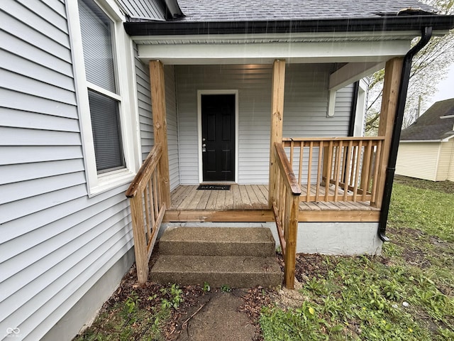 doorway to property featuring roof with shingles and covered porch