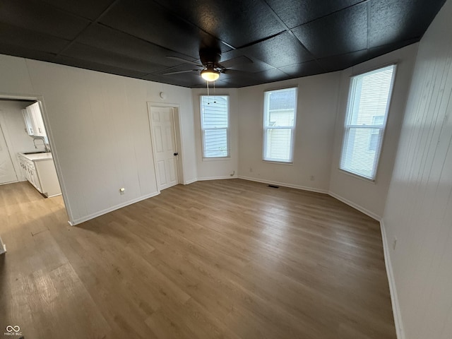 interior space with baseboards, a ceiling fan, and light wood finished floors