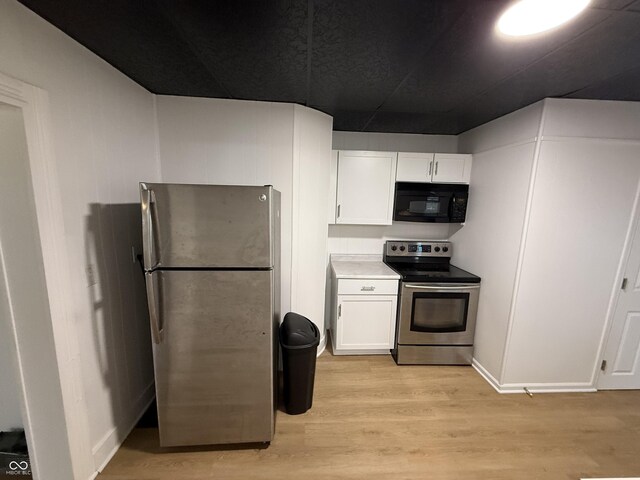 kitchen with white cabinets, light countertops, appliances with stainless steel finishes, and light wood finished floors