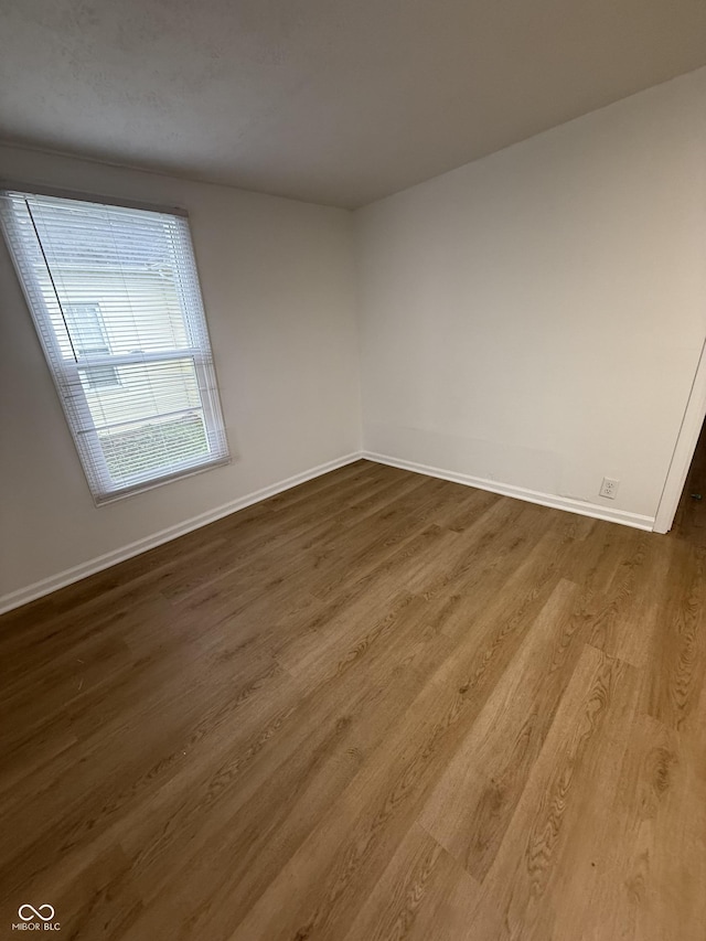 unfurnished room featuring baseboards and dark wood-type flooring
