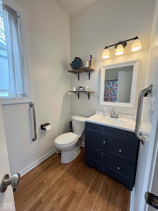 full bathroom featuring toilet, baseboards, wood finished floors, and vanity