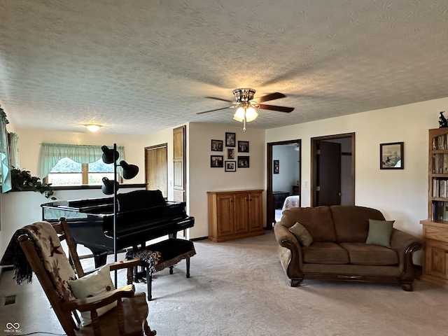 living area with light colored carpet, ceiling fan, and a textured ceiling