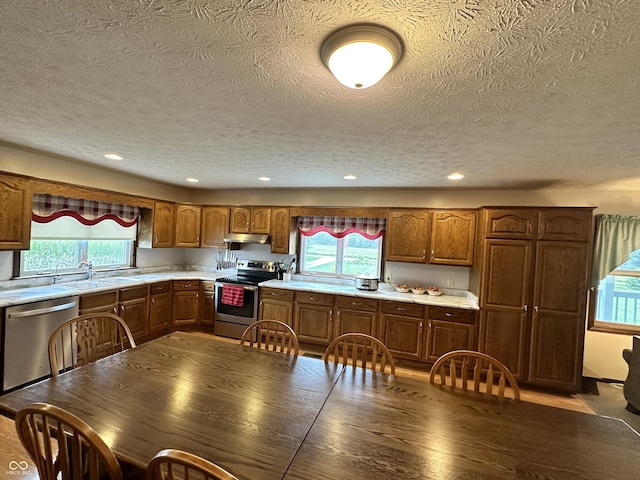 kitchen with under cabinet range hood, plenty of natural light, appliances with stainless steel finishes, and light countertops