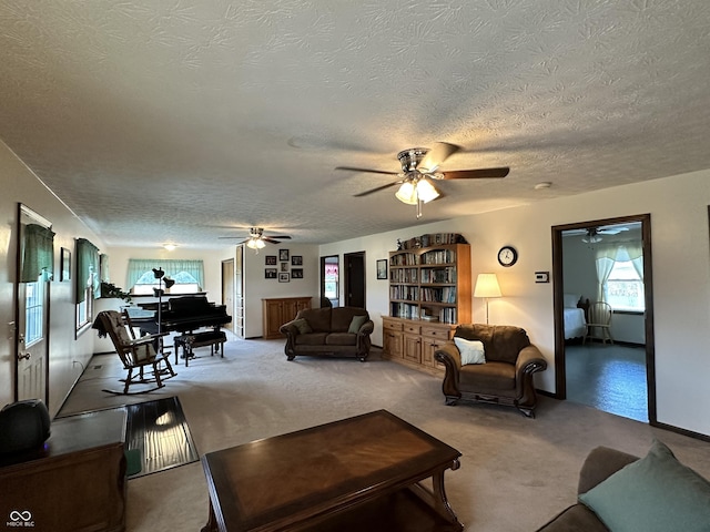carpeted living area with a textured ceiling and ceiling fan