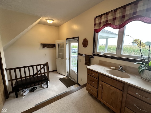 bathroom with vaulted ceiling, vanity, and baseboards