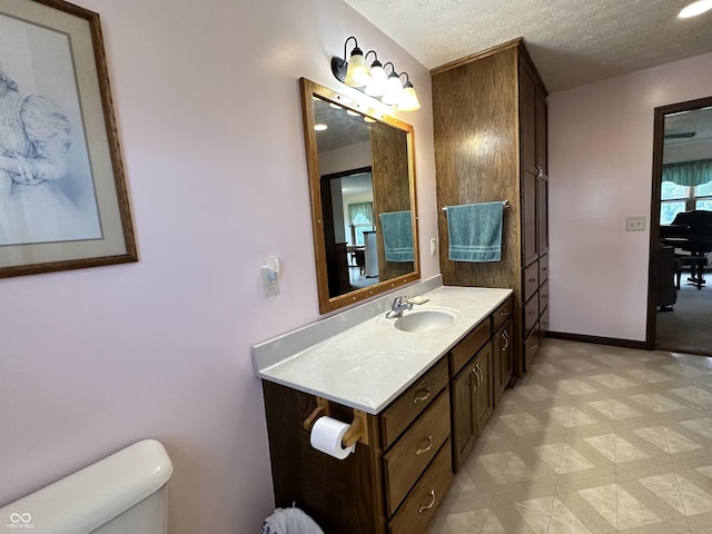 bathroom with tile patterned floors, toilet, vanity, baseboards, and a textured ceiling