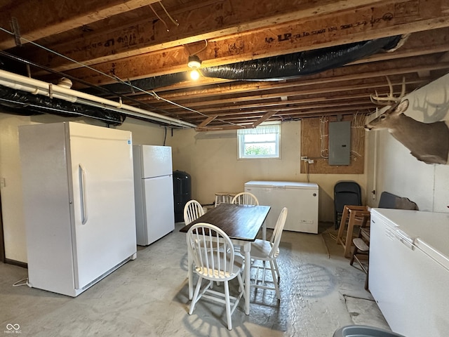 below grade area with freestanding refrigerator, fridge, electric panel, and independent washer and dryer
