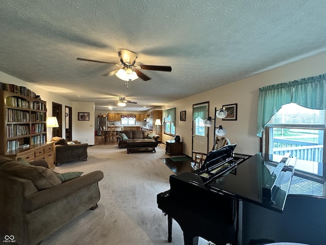 carpeted living area with a ceiling fan and a textured ceiling