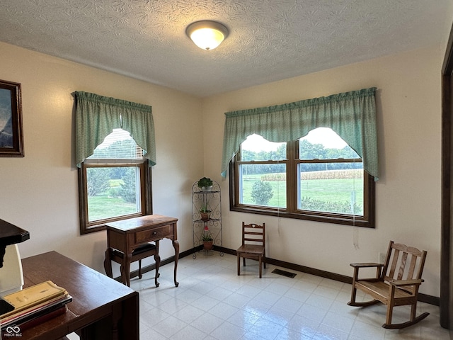 sitting room with baseboards, a healthy amount of sunlight, a textured ceiling, and visible vents