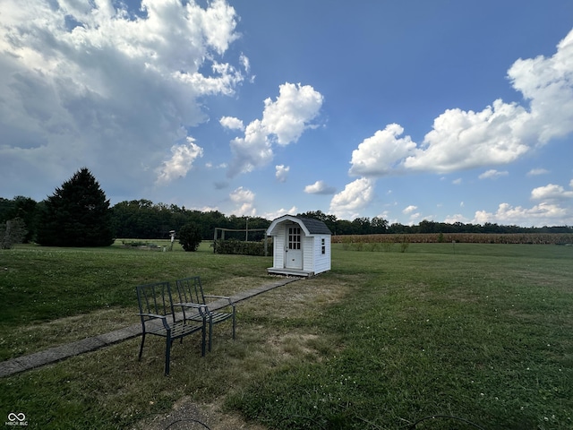 view of yard featuring a rural view, a storage unit, and an outbuilding