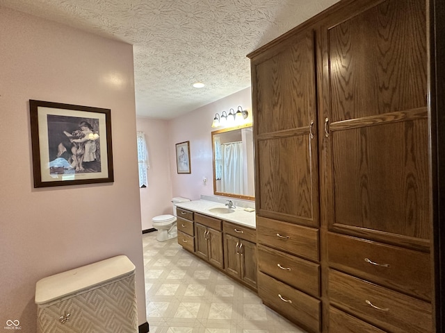 full bath with tile patterned floors, toilet, vanity, baseboards, and a textured ceiling