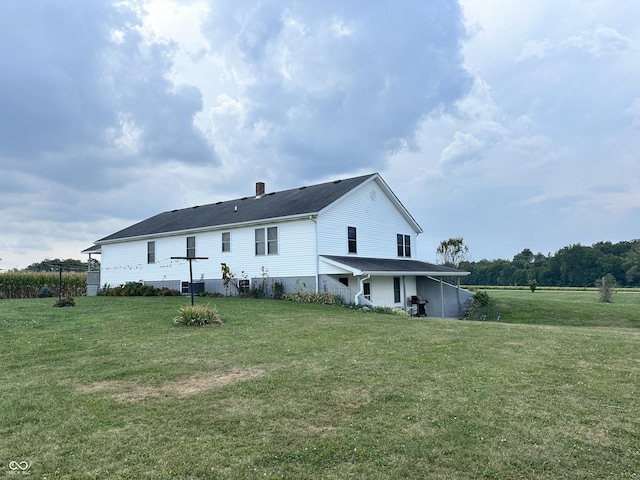 rear view of property with a lawn, a chimney, and central AC