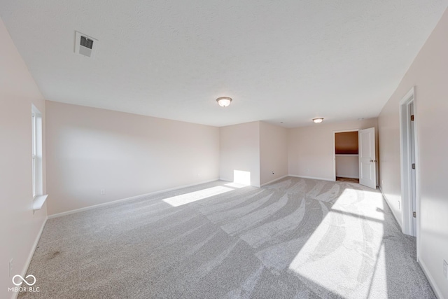 spare room with baseboards, visible vents, and light colored carpet