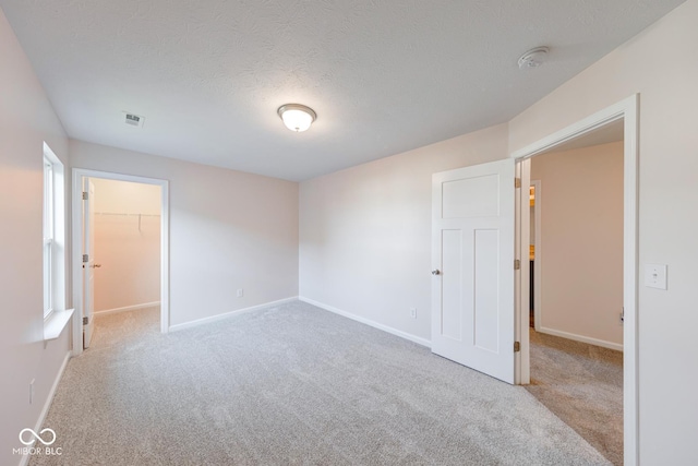 unfurnished room with carpet floors, visible vents, and baseboards