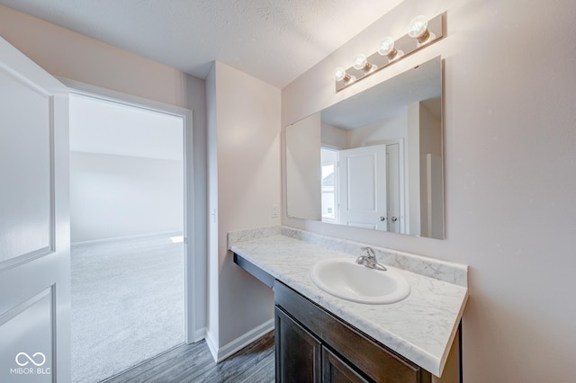 bathroom featuring baseboards, wood finished floors, and vanity