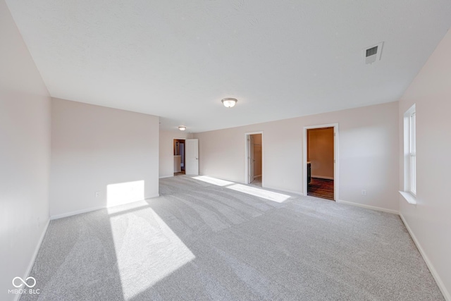 empty room featuring baseboards, visible vents, and light colored carpet