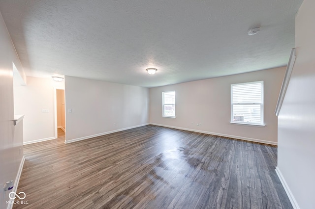 unfurnished room with baseboards, dark wood-style flooring, and a textured ceiling