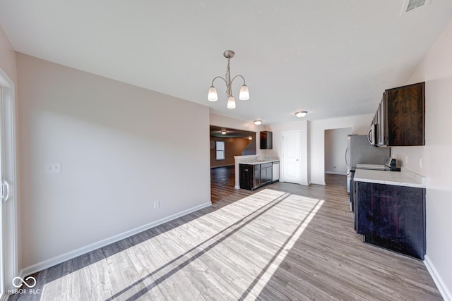 unfurnished living room featuring a chandelier, wood finished floors, visible vents, and baseboards
