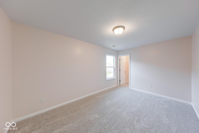 carpeted empty room featuring baseboards and a textured ceiling