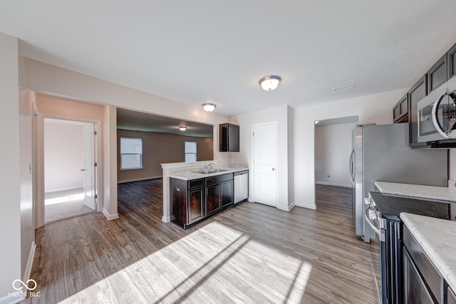 kitchen with baseboards, light wood-style flooring, stainless steel appliances, and light countertops